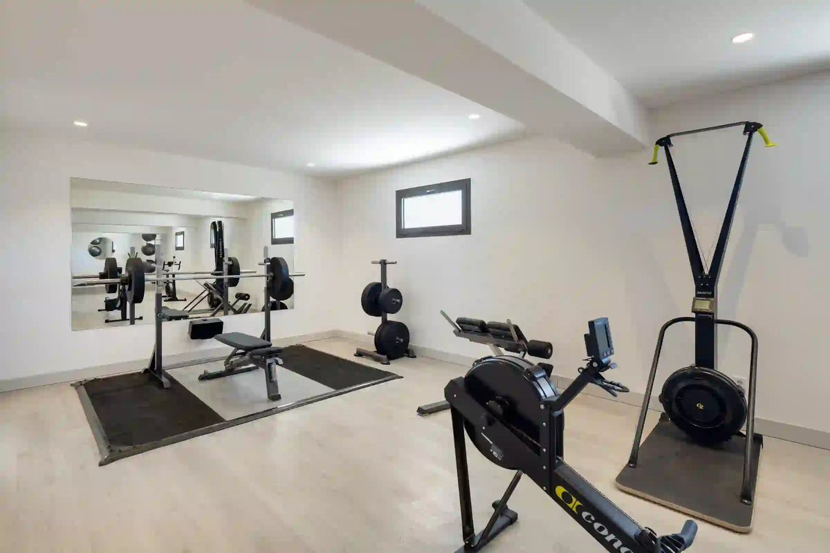 The villa gym, with a rowing machine, weights bench and mirrored wall.