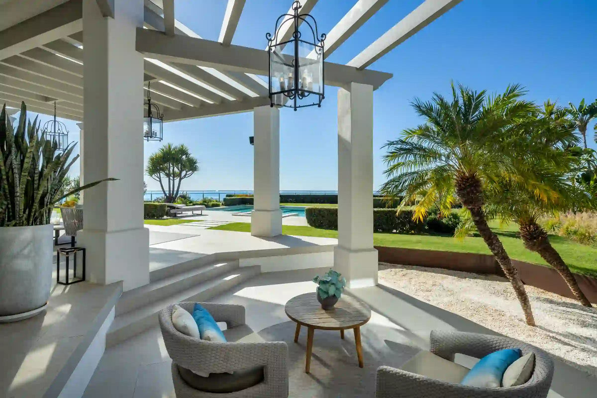 A shaded terrace with seating, looking out over the garden and the sea.