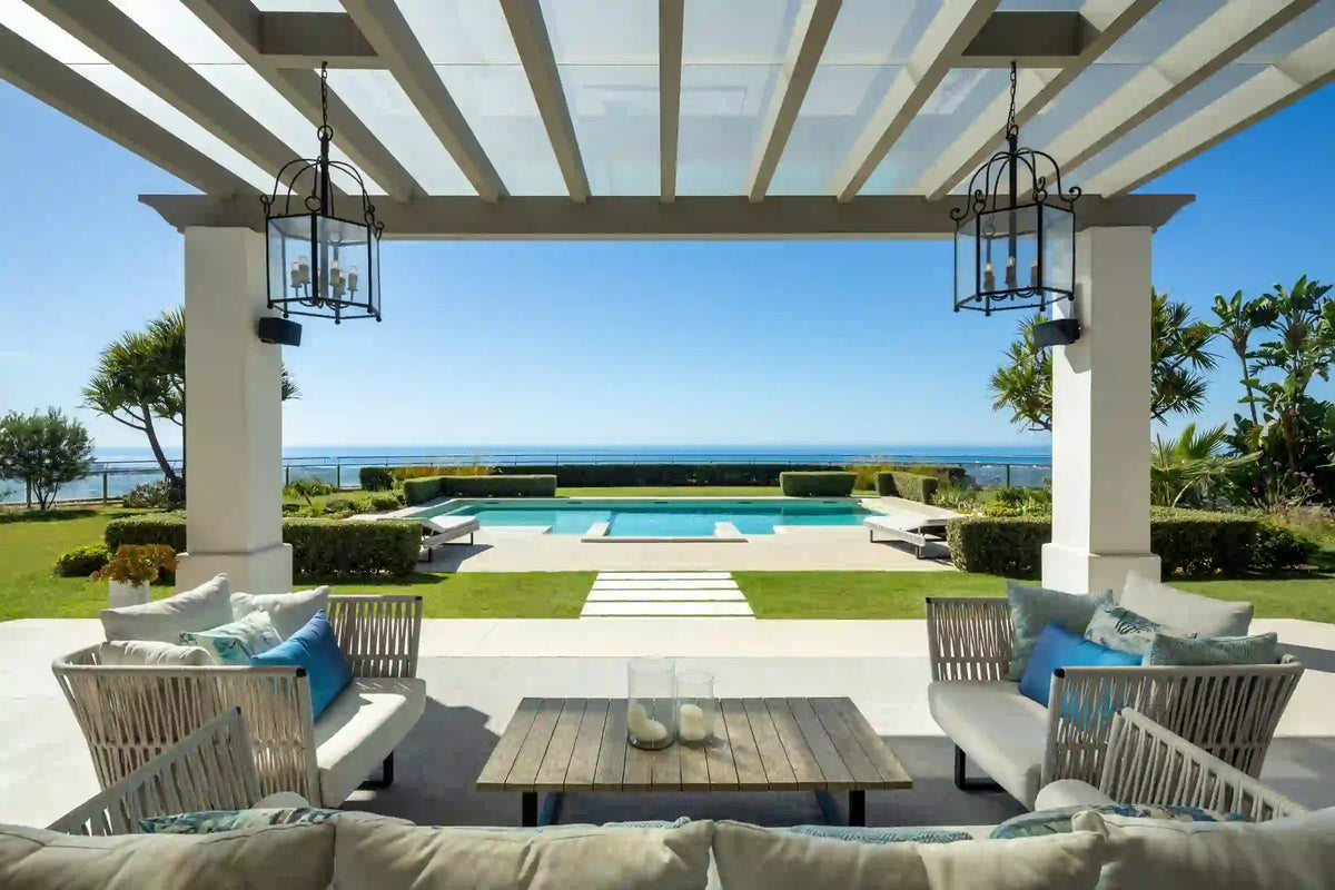 A covered terrace with sofas, looking out over the pool and the sea.
