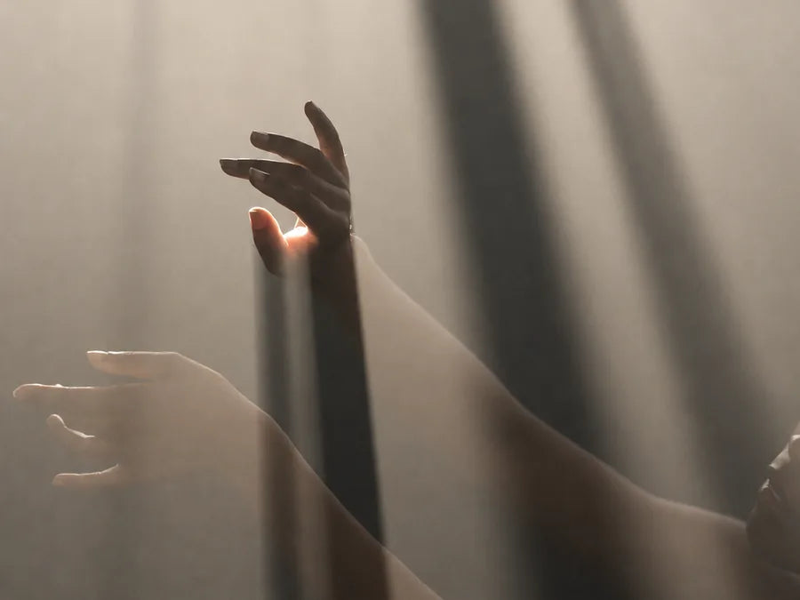 Hands reaching upward through soft light.